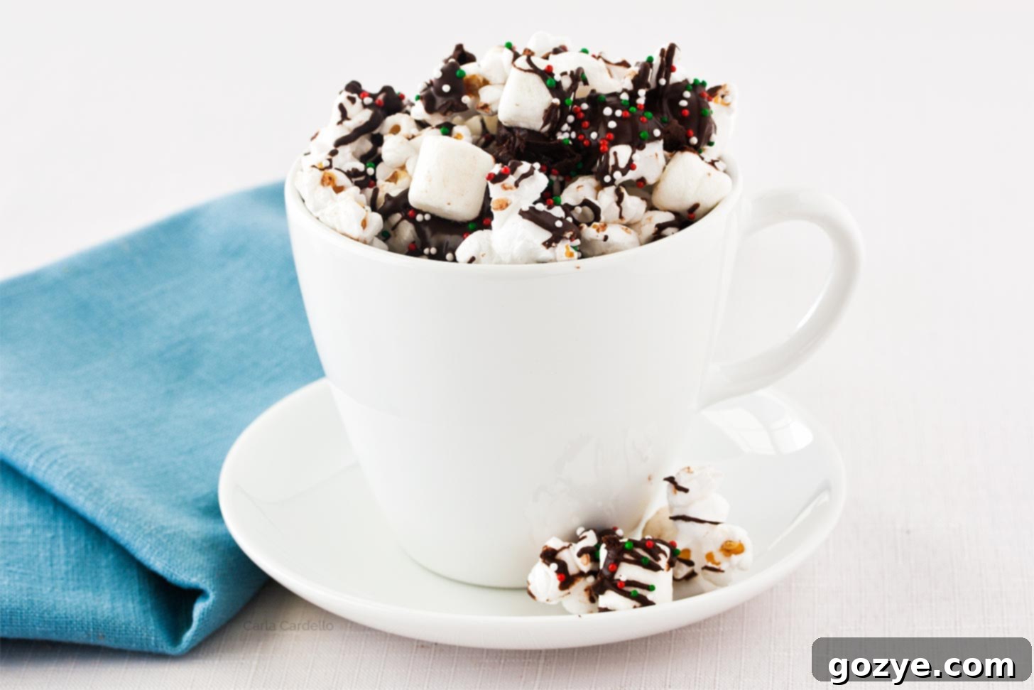 Sweet & Salty Popcorn Crunch 5 Chocolate covered popcorn in a white mug on a plate