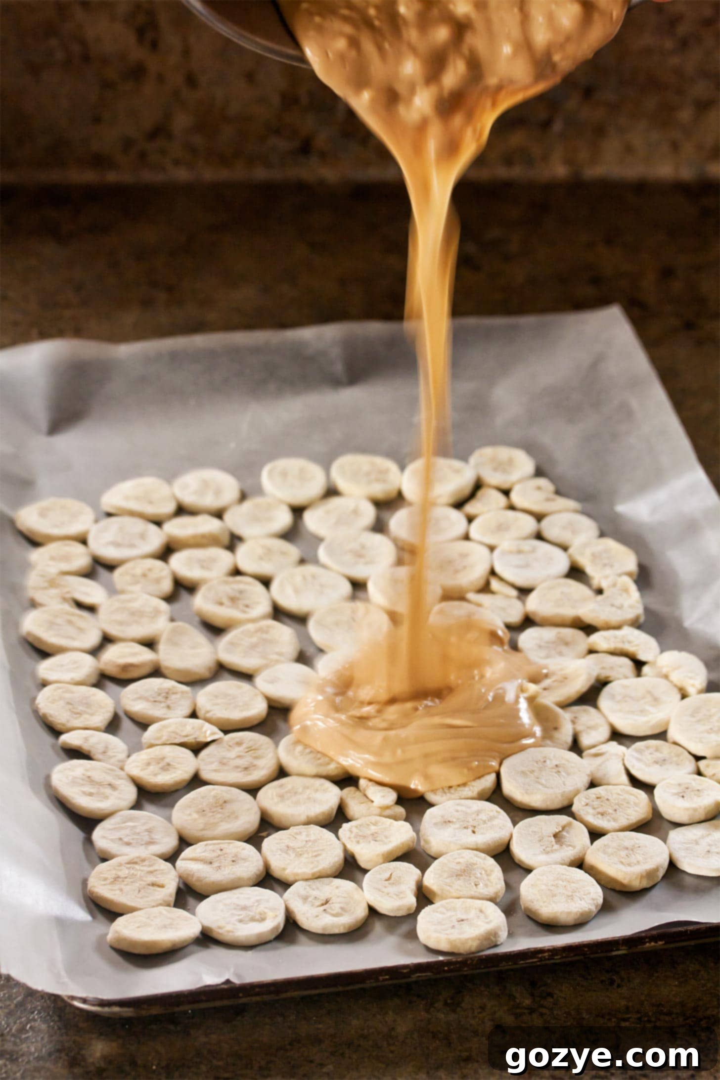 Pouring peanut butter chocolate over banana slices