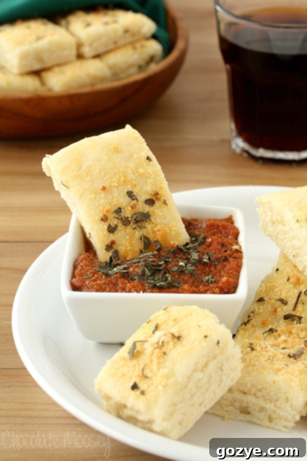 Close-up of Homemade Soft Garlic Parmesan Breadsticks with a bowl of rich Pepperoni Dipping Sauce