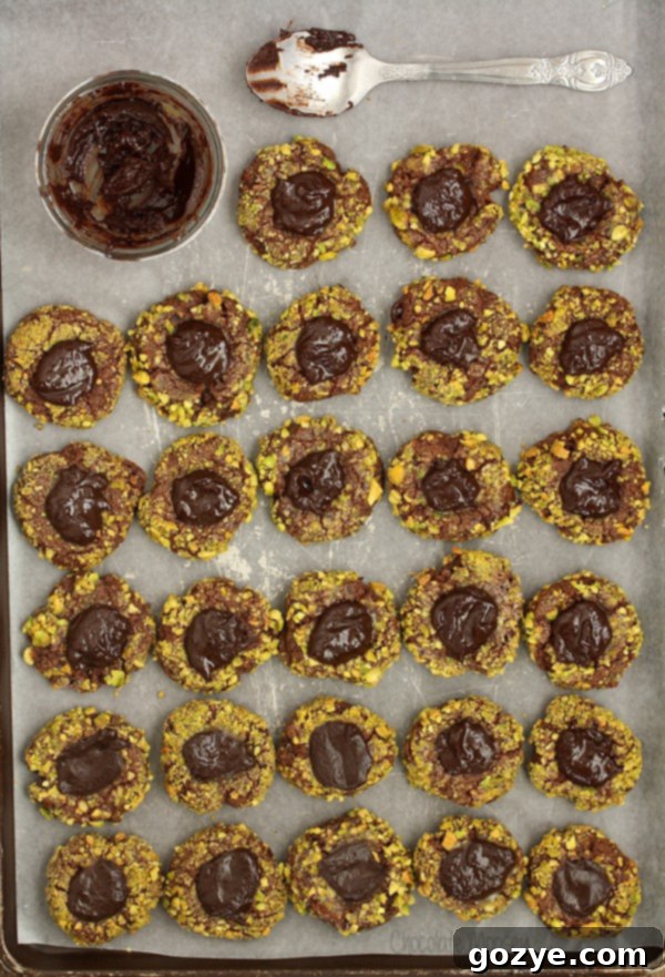 Close-up of freshly baked chocolate thumbprint cookies with vibrant green pistachios