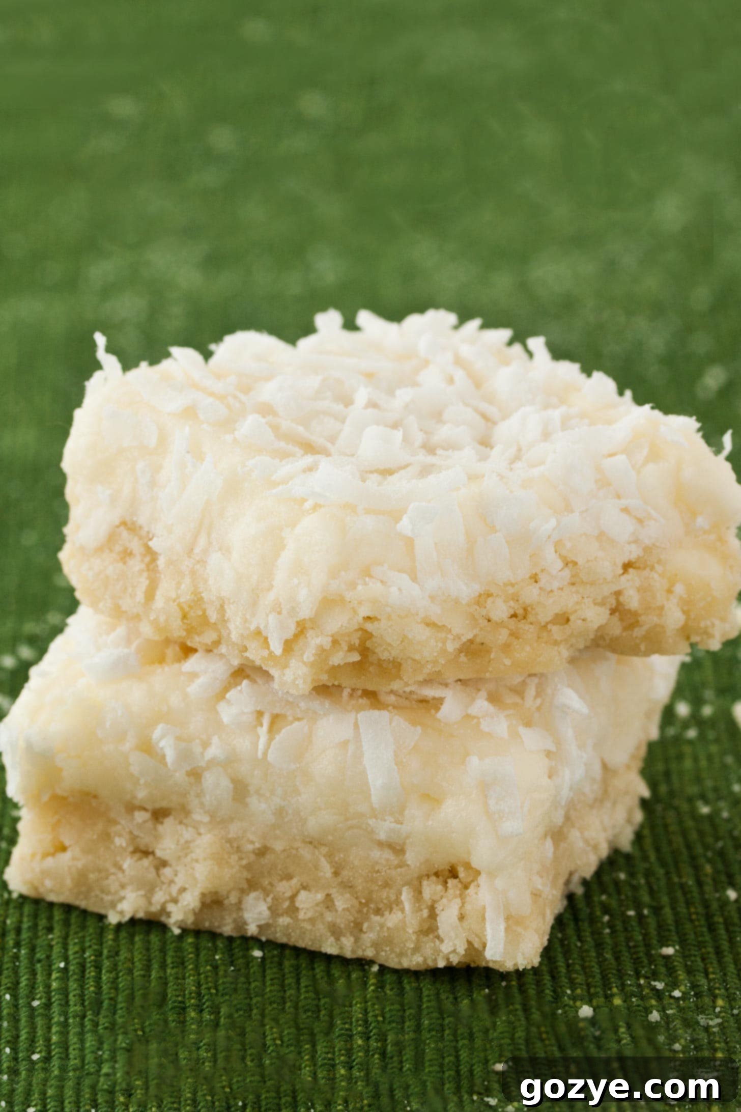 Coconut Cookie Bars stacked on top of each other with green background