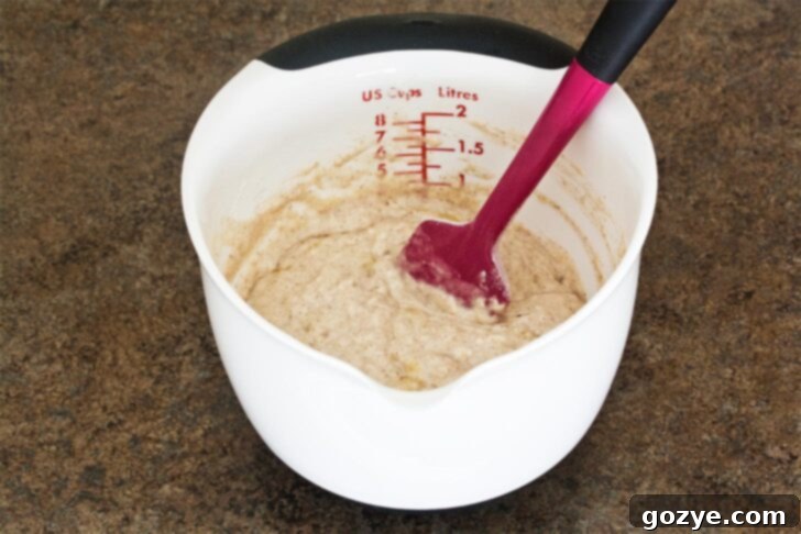 Dairy-Free Banana Coconut Milk Pancakes 5 Pancake batter for coconut banana pancakes in a bowl, showing its thick and slightly lumpy consistency, ready for cooking.