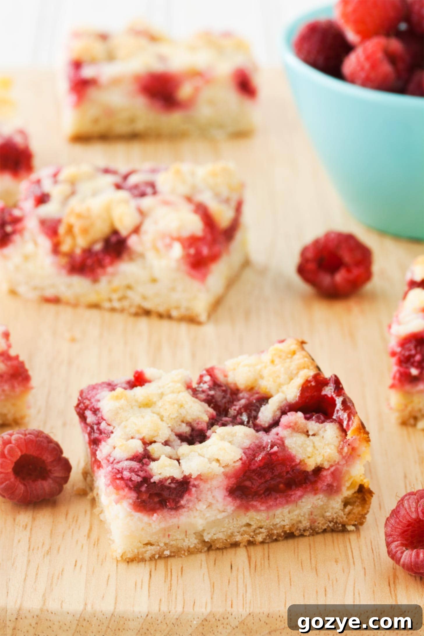 Raspberry Cream Cheese Bars with berries on a cutting board