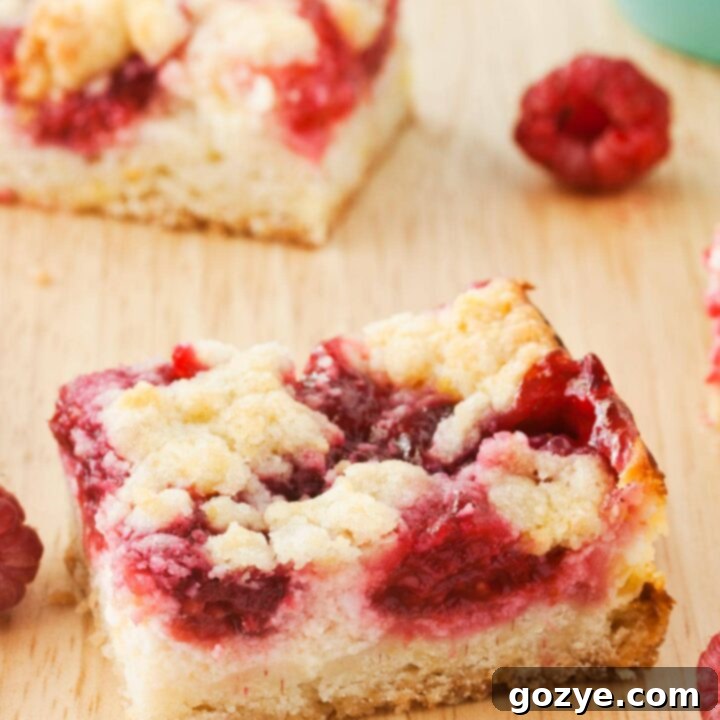 Raspberry Cheesecake Bars on a cutting board with berries