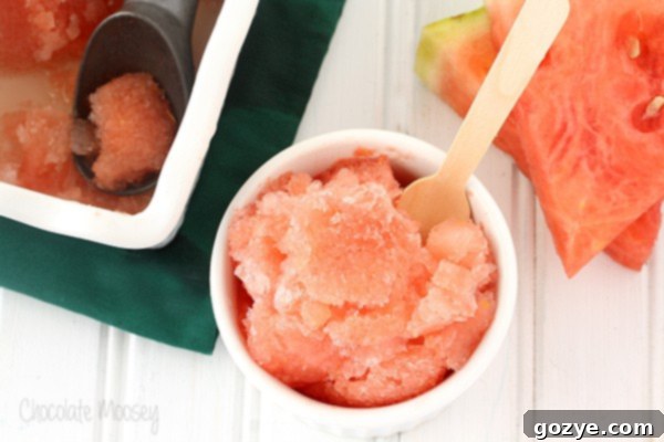 Close-up of a small white ramekin filled with homemade Watermelon Italian Ice, garnished with a wooden spoon.