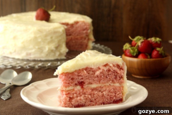 Detail shot of a delicious strawberry cake being frosted with homemade cream cheese frosting
