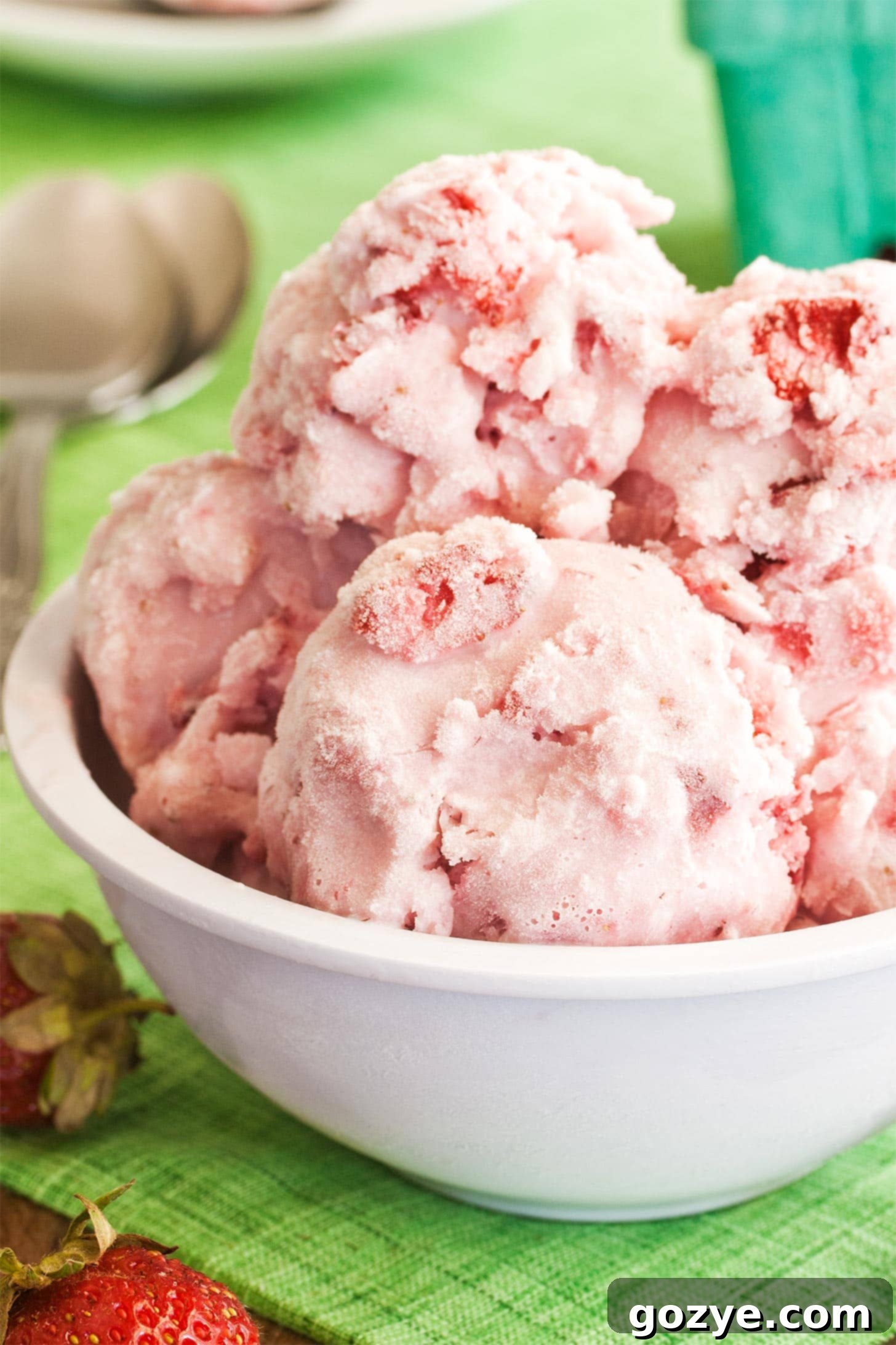 White bowl of luscious homemade strawberry ice cream, perfectly scooped and ready to enjoy on a light background.