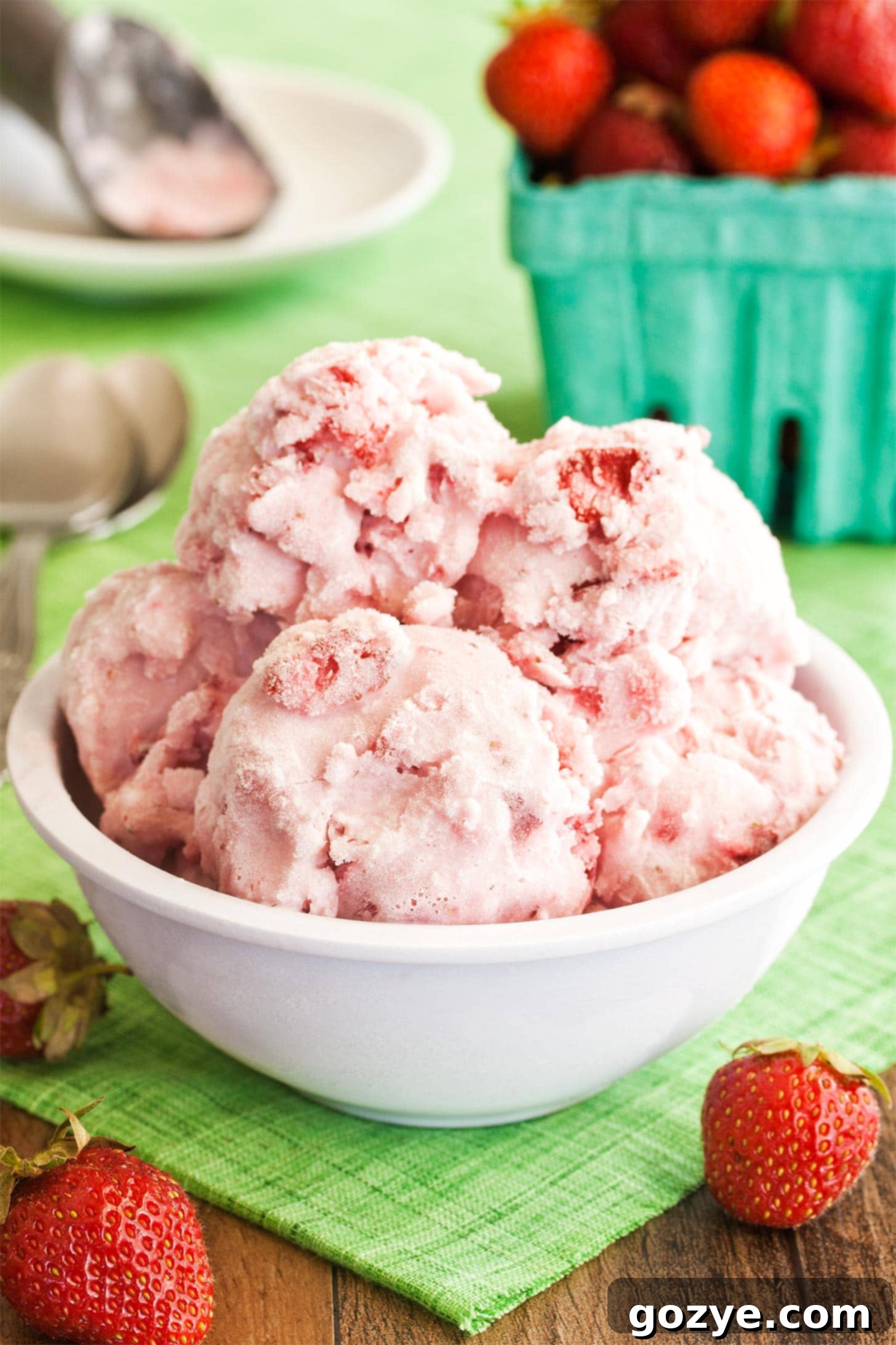 Bowl full of fresh strawberries and creamy ice cream scoops, garnished with whole strawberries.