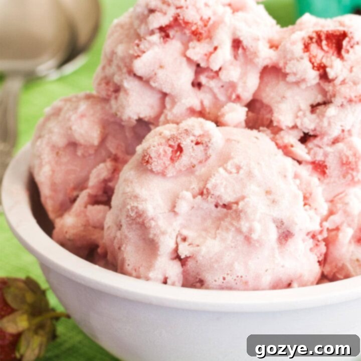 White bowl of strawberry ice cream, ready to serve with a spoon