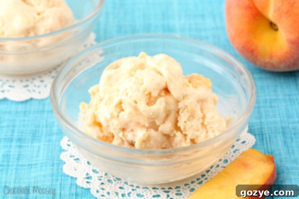 Close up shot of a single scoop of homemade peach ice cream, showing its smooth texture and small specks of peach fruit, served in a clear glass bowl.