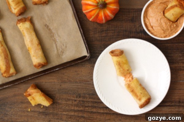 Heavenly Pumpkin Cheesecake French Toast Spirals 3 Close-up of golden-baked Pumpkin Cheesecake French Toast Roll Ups on a baking sheet, showcasing their perfectly rolled shape and a dusting of cinnamon sugar