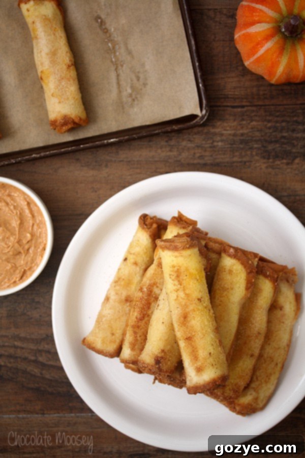 Heavenly Pumpkin Cheesecake French Toast Spirals 4 A stack of freshly baked Pumpkin Cheesecake French Toast Roll Ups, showcasing the delicious pumpkin cheesecake filling peeking out, ready for dipping