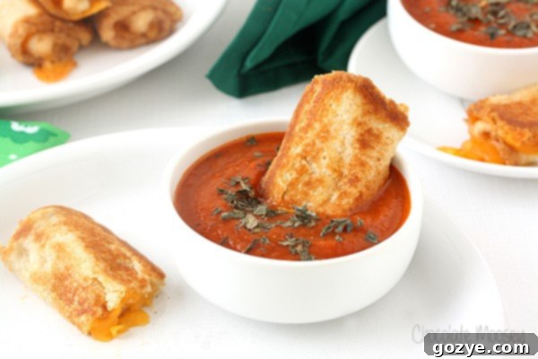 Cozy Grilled Cheese Roll-Ups with Tomato Soup Dip 6 Close-up of a single Grilled Cheese Roll Up being dipped into the creamy Tomato Soup Dipping Sauce, highlighting the melted cheese.