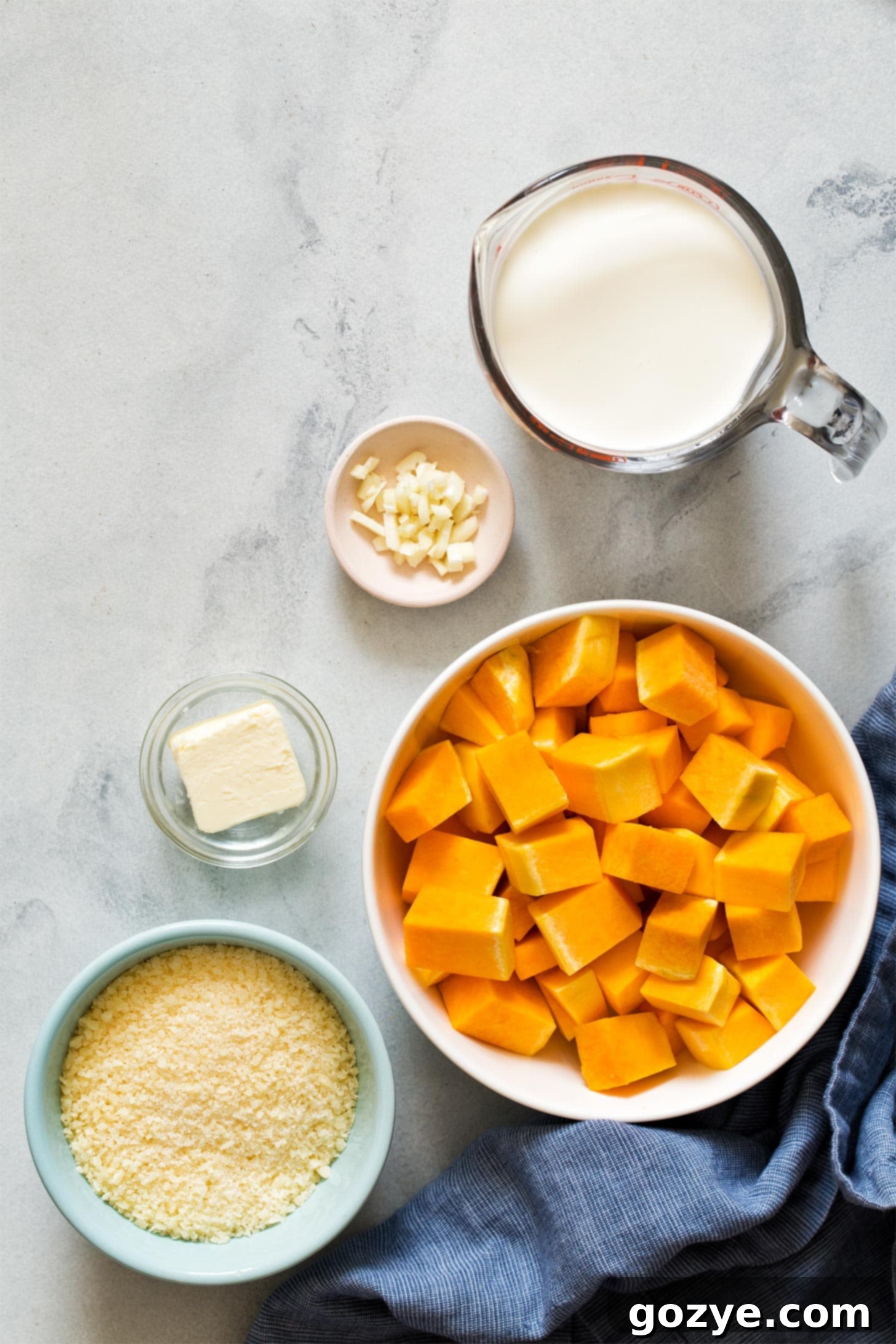 Ingredients for Butternut Squash Alfredo Sauce laid out on a wooden surface