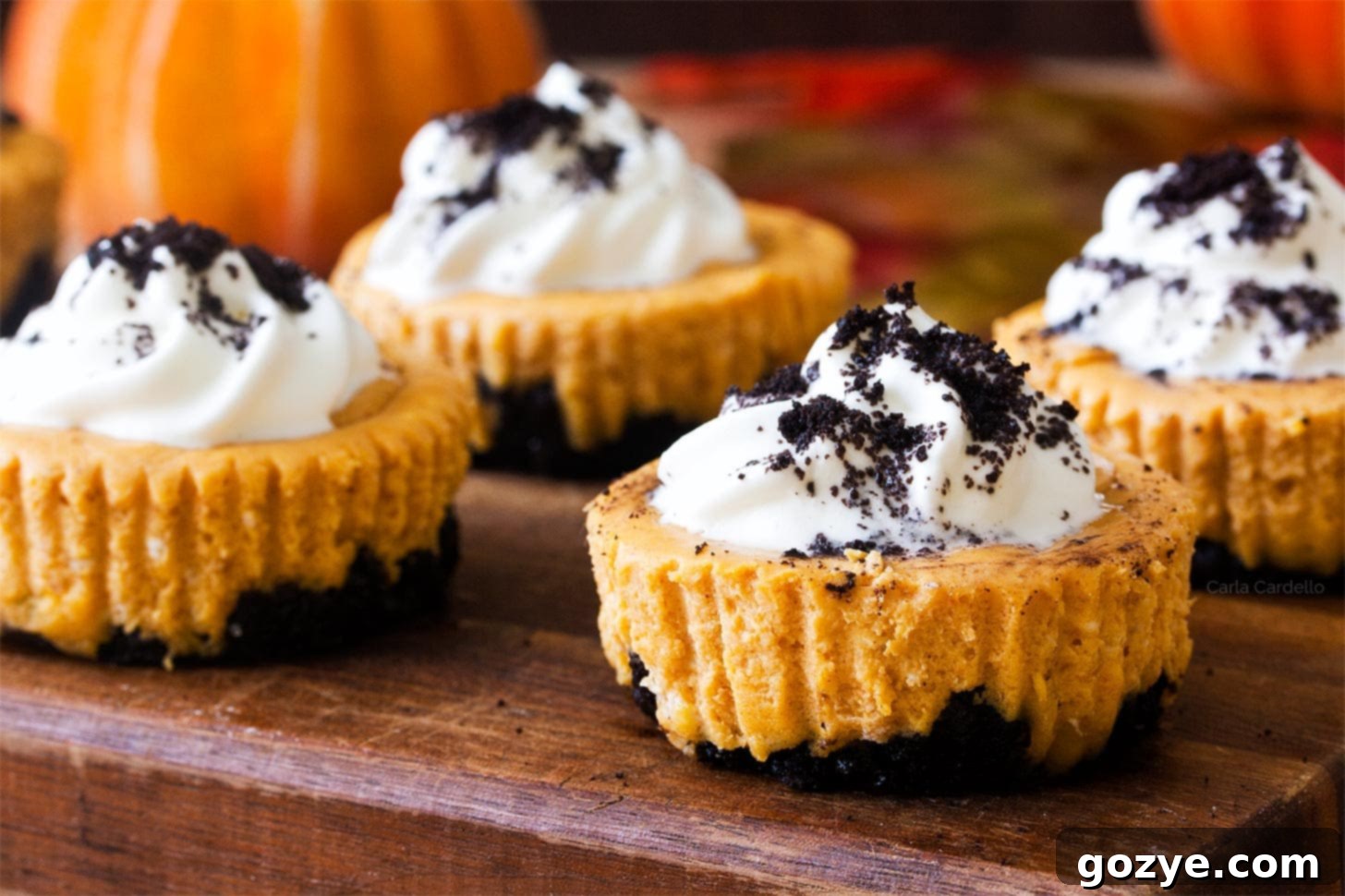 Mini pumpkin cheesecakes with oreo crust on a wooden cutting board