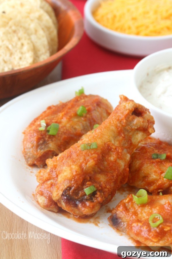 A plate of Saucy Taco Baked Chicken Wings, glistening with homemade taco sauce and garnished with fresh green onions