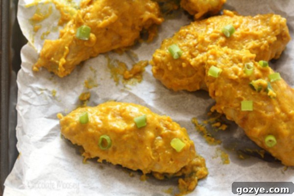 Another close up of a curry chicken wing, showcasing the texture of the sauce and the crispy skin, on a baking sheet