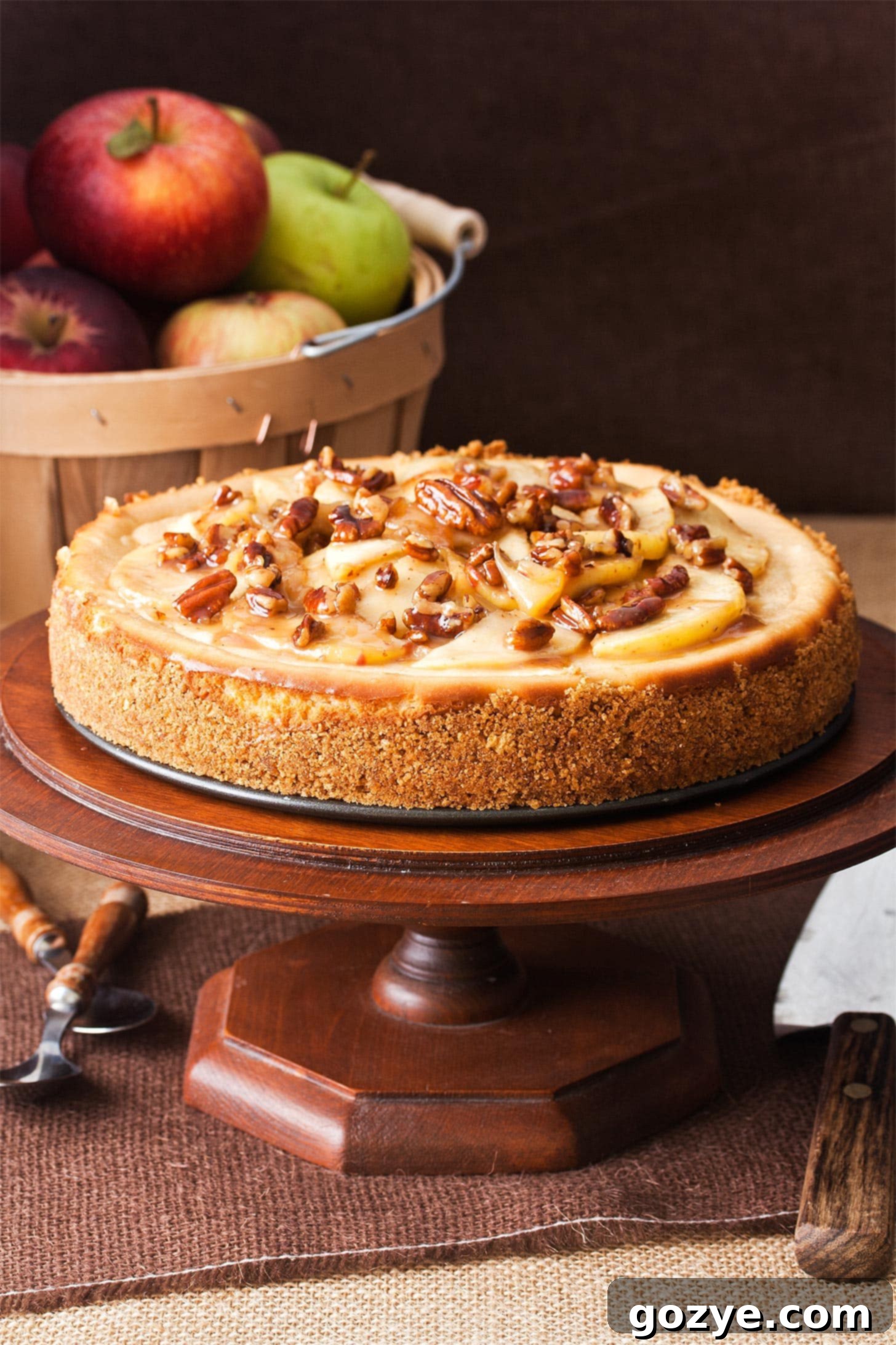 Whole caramel apple cheesecake on wooden cake stand