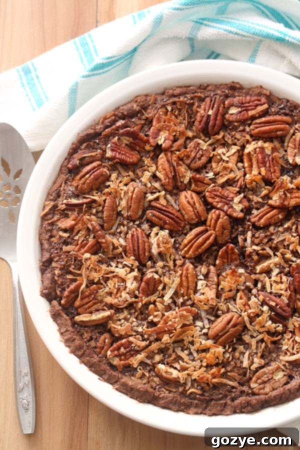 An overhead view of the full German Chocolate Pecan Pie nestled in a white ceramic pie plate, showcasing its golden-brown topping.