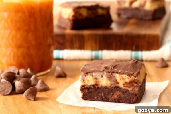 Close-up of a cut Caramel Chocolate Chip Cookie Dough Brownie showing distinct layers of brownie, cookie dough, and chocolate.
