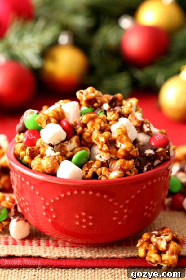 Festive Christmas Popcorn 2 Christmas Popcorn in red bowl with mini marshmallows, M&Ms, and chocolate drizzle
