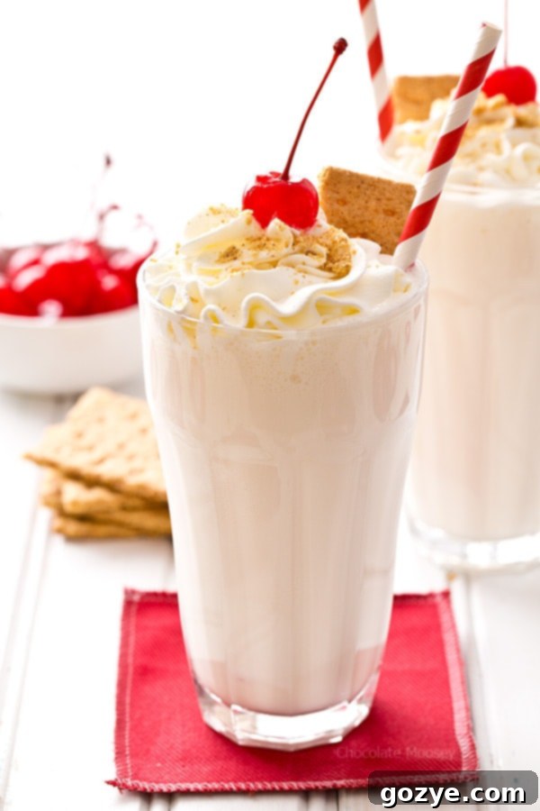 Decadent Cheesecake Shakes 2 Creamy Cheesecake Milkshakes in tall glasses, garnished with whipped cream, cherries, and graham cracker crumbs
