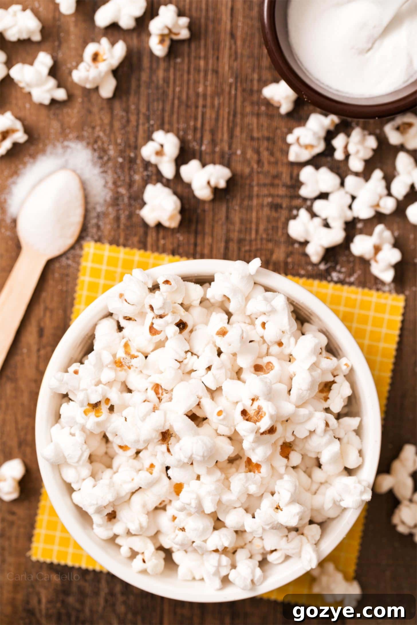Close-up of fluffy popcorn seasoned generously with white salt and vinegar powder, showing the distinct texture.