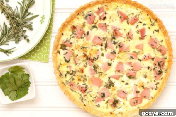 Close-up of Ham and Herb Quiche for brunch, showing cheesy goodness and a sprinkle of fresh herbs