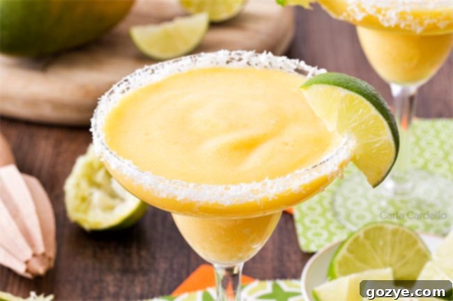 Close-up of a perfectly blended mango margarita with a lime wedge