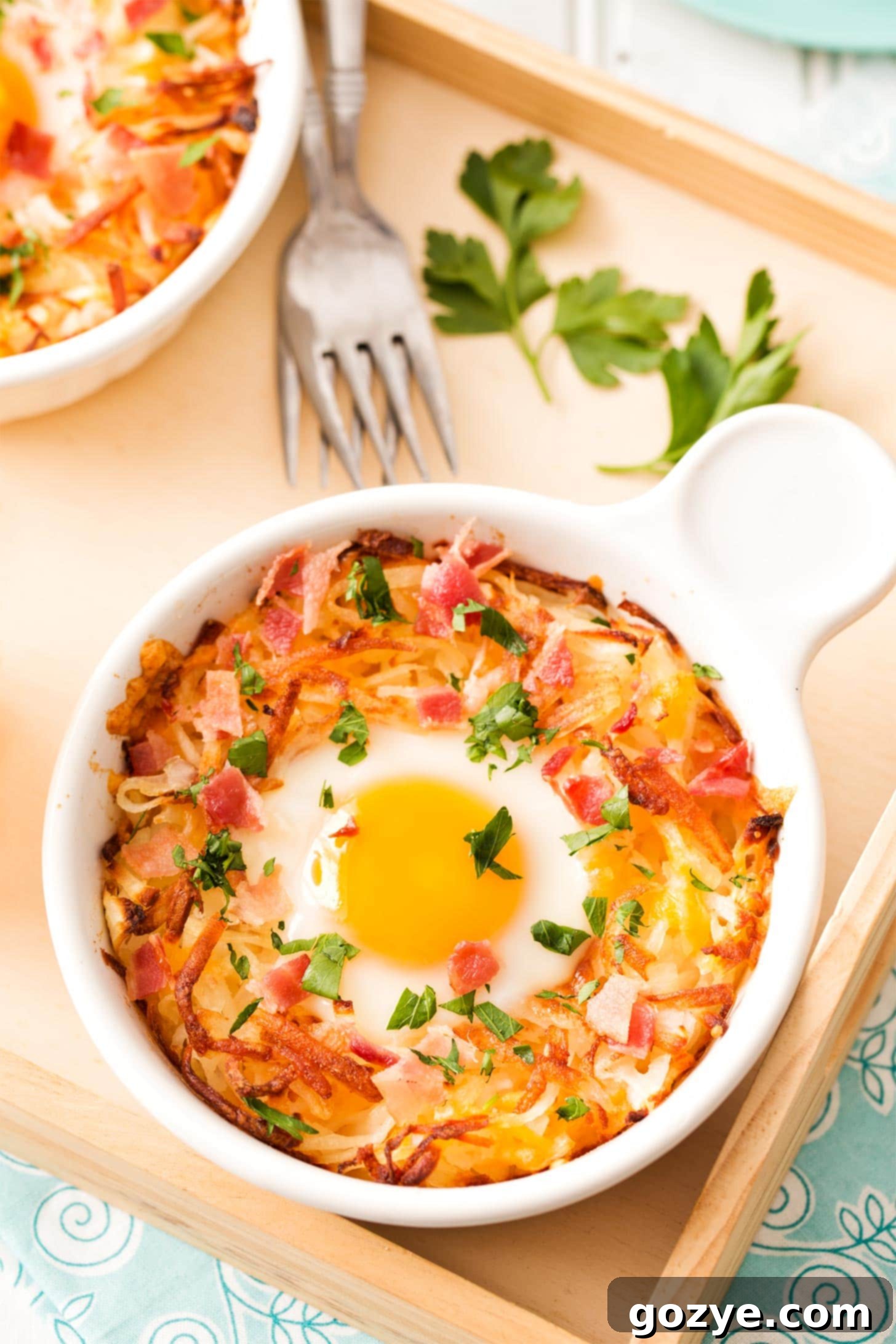 Hash Brown Bowls featuring crispy hash browns, a perfectly baked egg, and crumbled bacon, garnished with fresh herbs