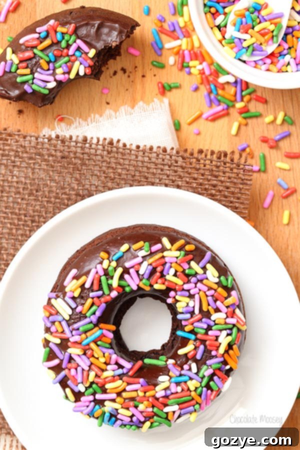 Three Triple Chocolate Baked Doughnuts arranged beautifully on a cooling rack, showcasing their glaze and sprinkles