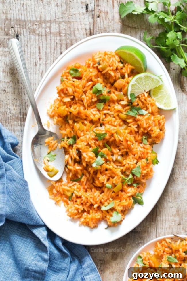 White platter with fluffy homemade Spanish rice, garnished with fresh cilantro and lime wedges.