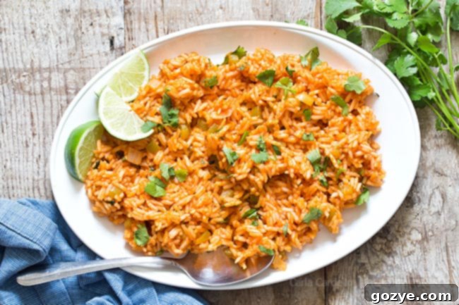 Spanish Rice on a white platter, garnished with fresh cilantro and lime slices, ready to be served.