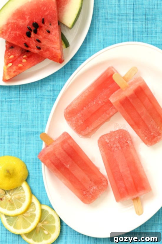 Vibrant Watermelon Margarita Popsicles on a white plate with lemon slices, ready to be enjoyed