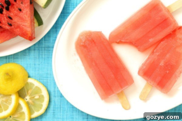A trio of beautifully crafted Watermelon Margarita Popsicles, each with a light dusting of sea salt, presented on a pristine white plate