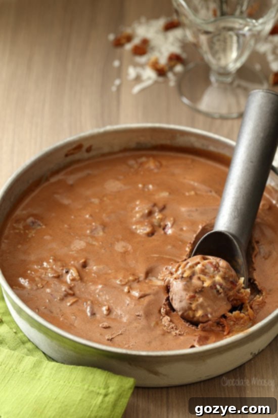 Close-up of creamy German Chocolate Cake Ice Cream with a scoop, showing enticing swirls of coconut-pecan frosting