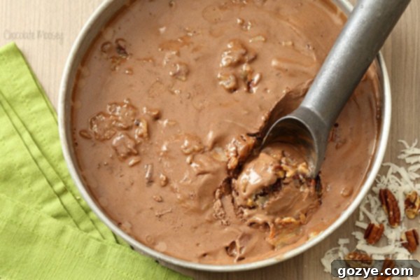 Scoop of German Chocolate Cake Ice Cream garnished with chopped pecans and shredded coconut in a white bowl
