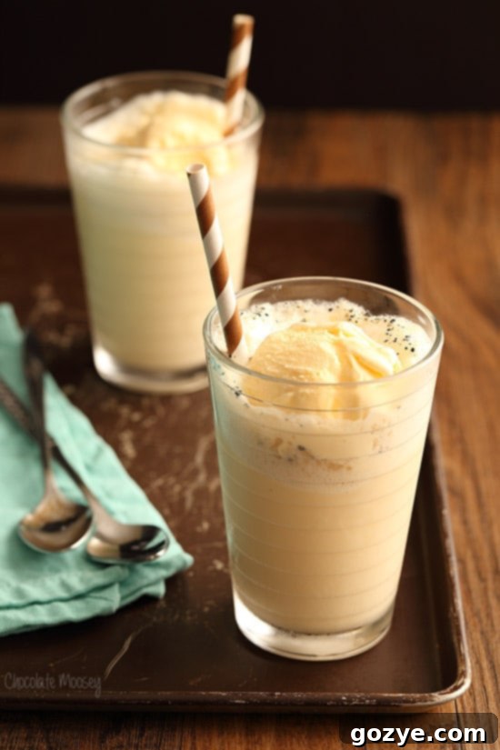 Two glasses of Vanilla Bean Cream Soda Floats, topped with ice cream and a straw, ready to be enjoyed.