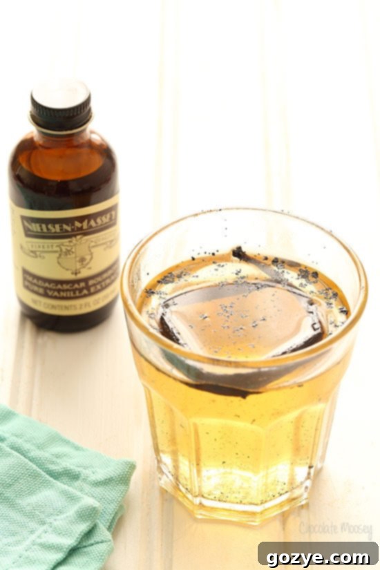 Close-up of homemade cream soda syrup, infused with a split vanilla bean pod, resting in a glass jar.