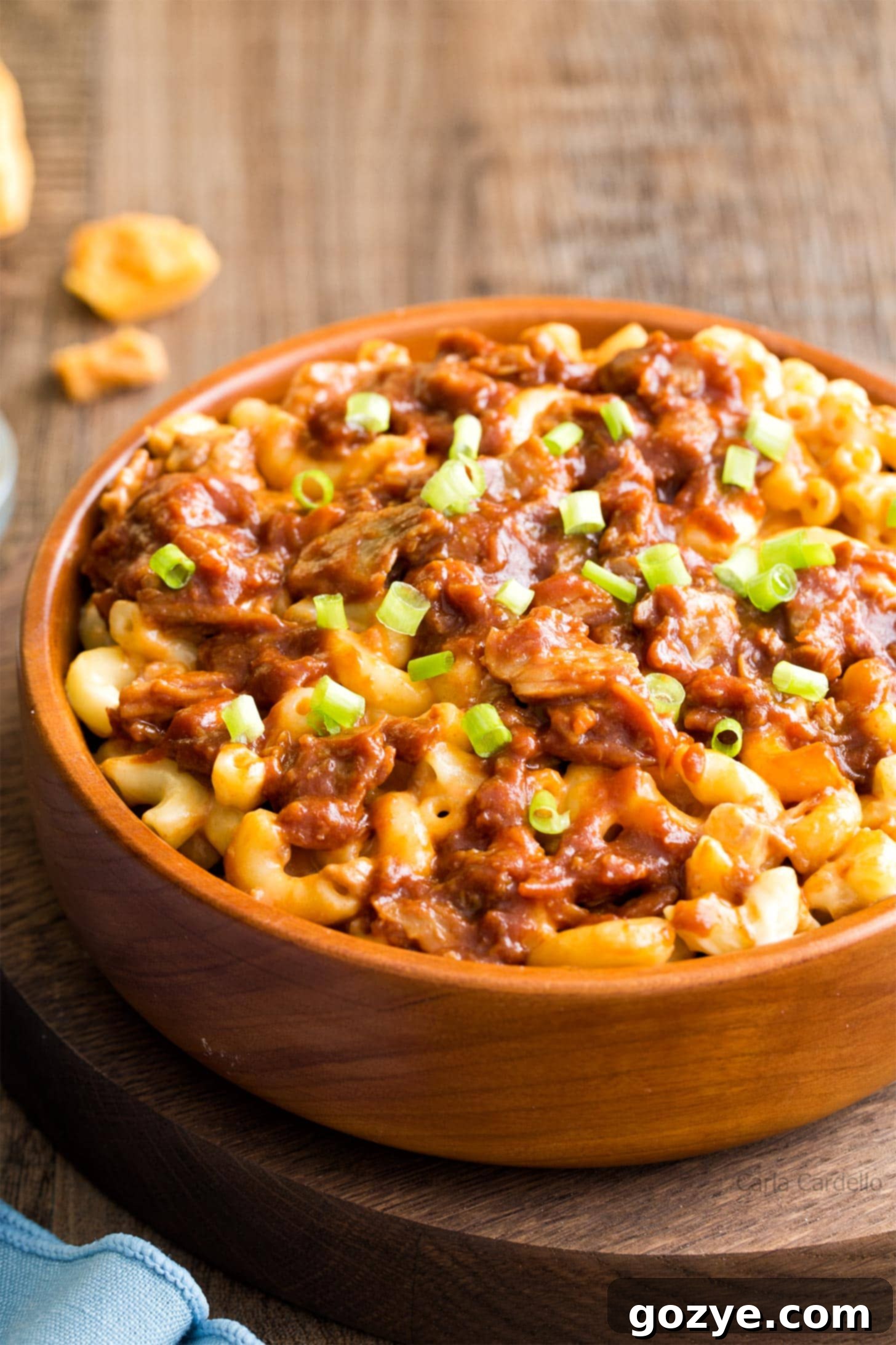 Ultimate Pulled Pork Mac and Cheese 3 Close up shot of creamy pulled pork mac and cheese in a brown bowl, garnished with green onions