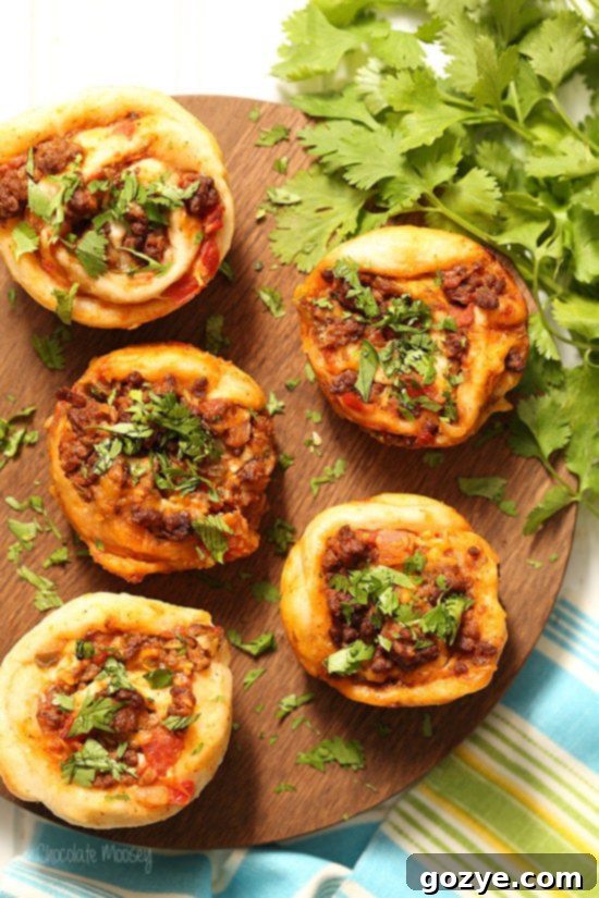 Delicious Taco Pizza Roll Ups with seasoned ground beef, vibrant salsa, and melted cheese, garnished with fresh cilantro, ready to be served for a party or dinner.