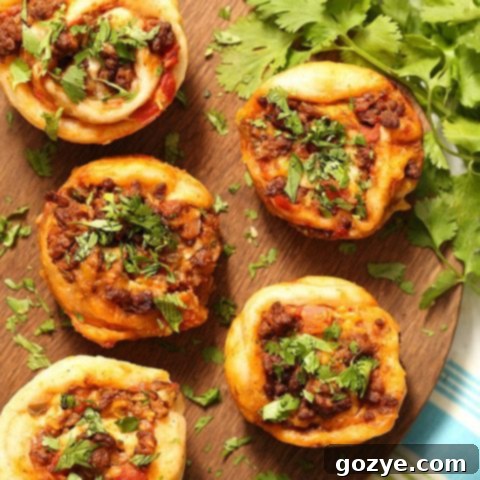 Homemade Taco Pizza Rolls, golden brown and garnished with fresh cilantro, served in a muffin tin and ready to enjoy.