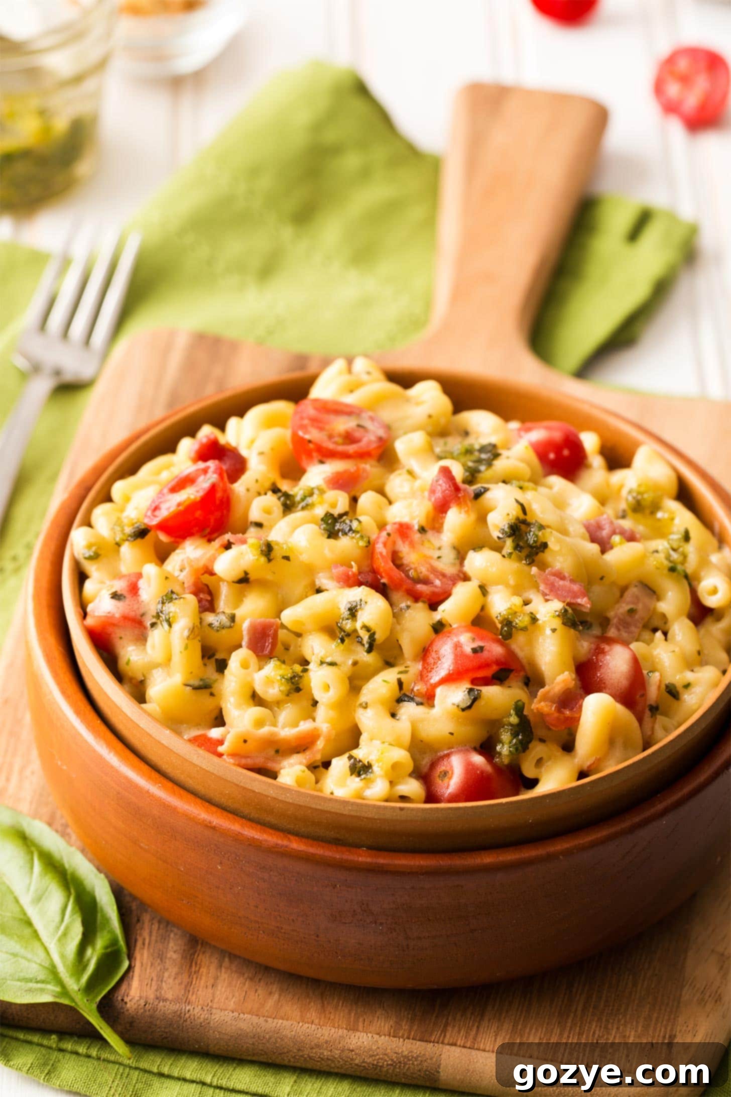 Pesto mac and cheese with bacon served in a brown bowl