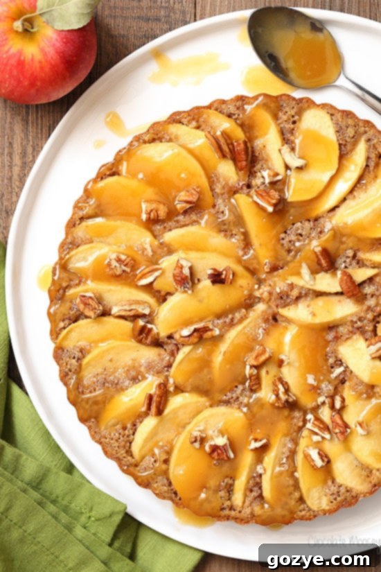 A stunning Caramel Apple Pecan Tart, showcasing thinly sliced apples, pecans, and caramel, presented in a fluted tart pan. This tart is actually a delicious apple cake recipe.