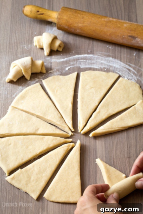 Hands rolling up crescent roll dough into its iconic shape