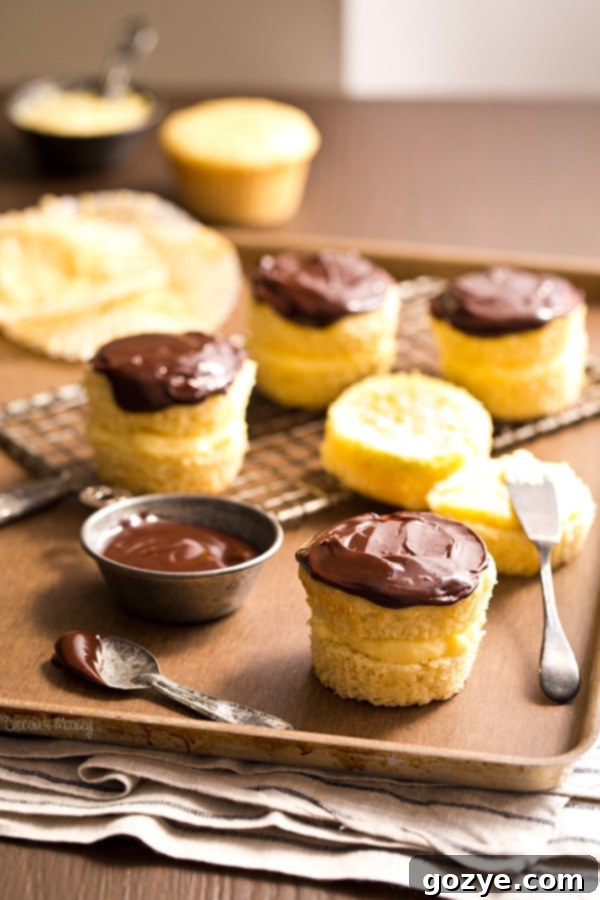 Small Batch Boston Cream Pie Cupcakes 2 Small Batch Boston Cream Pie Cupcakes, elegantly arranged on a serving plate, showcasing their golden cake, creamy custard, and glossy chocolate ganache.