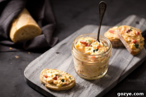 A close-up of pimento goat cheese spread on crostini, garnished with green onion