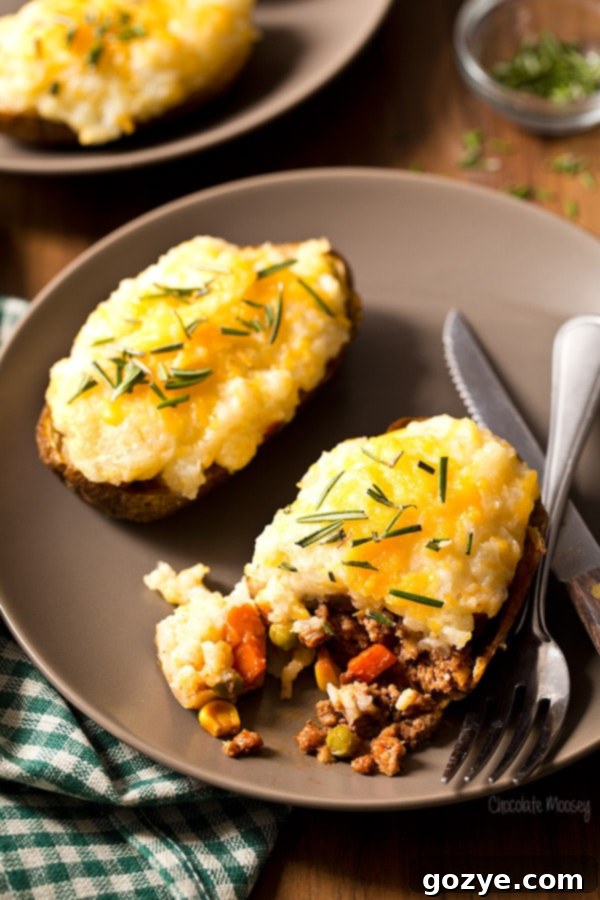 Shepherd's Pie Baked Potatoes cut open on a plate, showcasing the meat and potato layers.