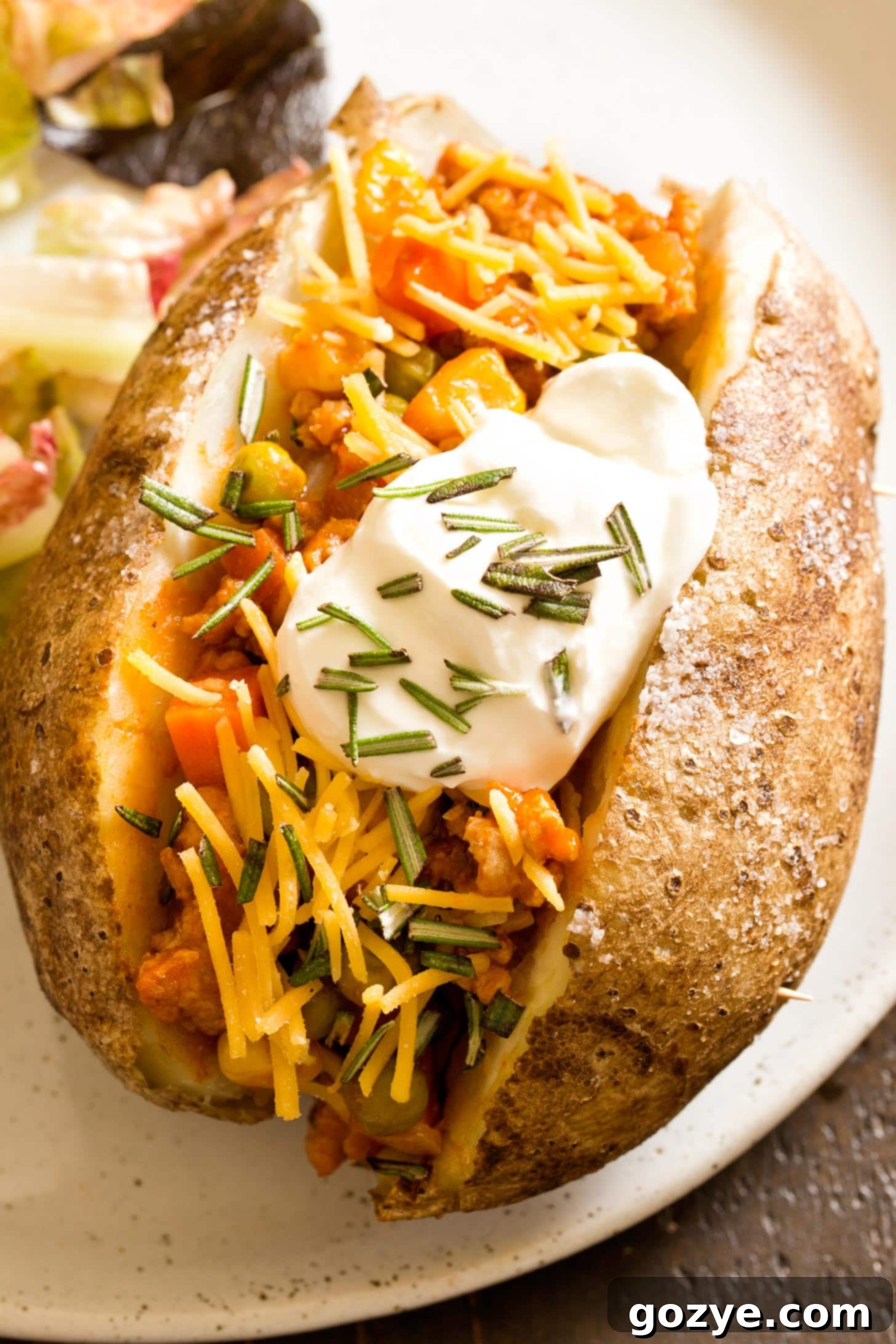 Close up of a shepherd's pie baked potato, showing the mashed potato topping and savory filling.