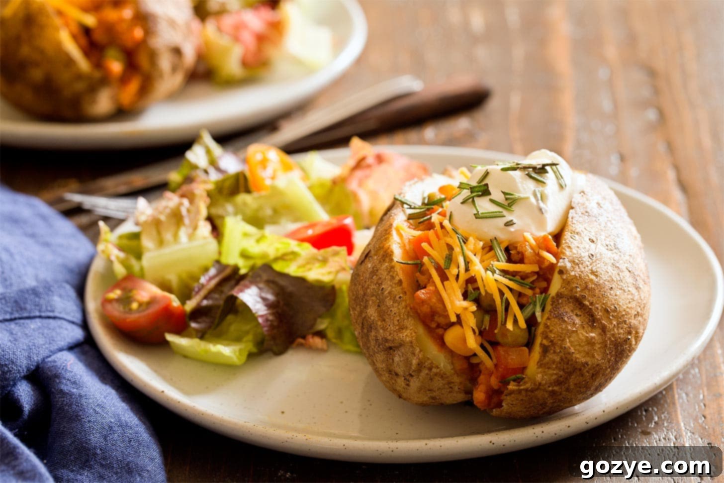 Cottage pie baked potato served on a plate with a fresh side salad.